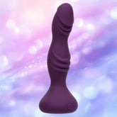 The CalExotics Deep Stud Vibrating Probe, a purple personal massager made from body-safe silicone with a curved, ribbed design and flared base, is displayed against a softly blurred pink and purple background.